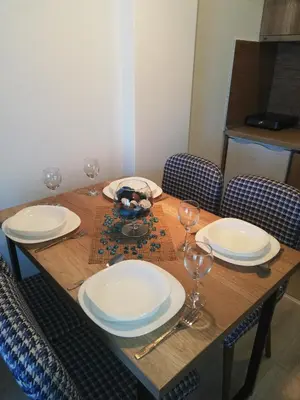 a wooden table with plates and wine glasses on it at Apartman Adelfes P16, Milmari Resort in Kopaonik