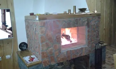 a stone fireplace with a fire in it at Seosko turisticko domaćinstvo Jagor in Despotovac