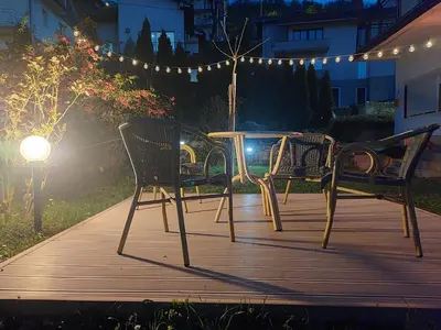 three chairs and a table on a deck at night at Sokobanja Smeštaj Pavlović & privatan parking in Soko Banja