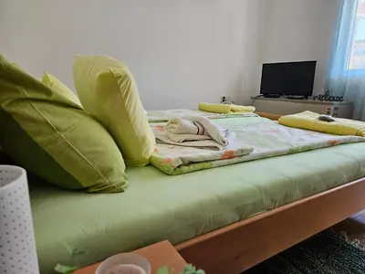 a bed with green sheets and pillows on it at Sokobanja Smeštaj Pavlović & privatan parking in Soko Banja