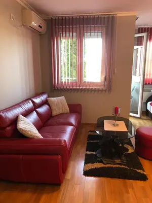 a living room with a red leather couch and a table at Studio Mišel 2 in Vrnjačka Banja