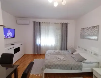 a white bedroom with a bed and a television at Apartman - Studio Prnic in Soko Banja