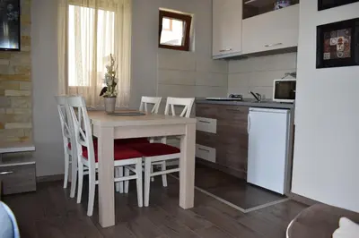 a kitchen with a table and chairs in a room at Apartman G1 u Milmari kompleksu - Kopaonik in Kopaonik