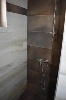 a bathroom with a shower with brown tiles at Apartman G1 u Milmari kompleksu - Kopaonik in Kopaonik