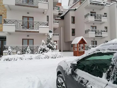 a snow covered car parked in front of a building at Apartman G1 u Milmari kompleksu - Kopaonik in Kopaonik