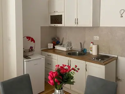a kitchen with white cabinets and a vase of flowers at Apartmani CENTAR Vrnjacka Banja & Free Parking in Vrnjačka Banja