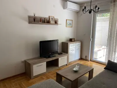 a living room with a tv and a couch and a table at Apartmani CENTAR Vrnjacka Banja & Free Parking in Vrnjačka Banja