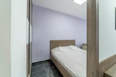 a bedroom with a bed with white sheets and a mirror at Dream House in Kruševac