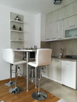 a kitchen with a table and two white chairs at Vila Irina - Studio 15 lux in Kopaonik
