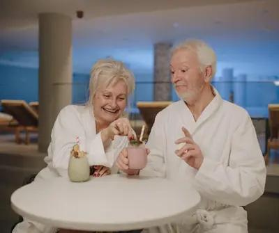 a man and woman sitting at a table with a drink at Pegaz Holiday Resort in Vrnjačka Banja