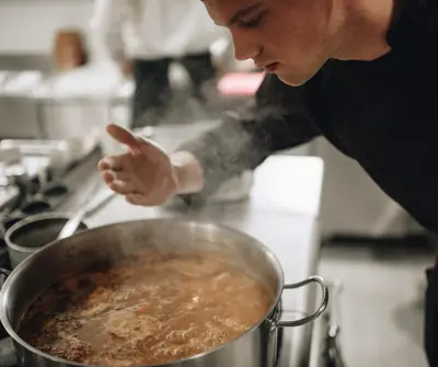 a man in a kitchen stirring a pot of food at Pegaz Holiday Resort in Vrnjačka Banja