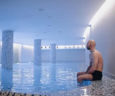 a man sitting in the water in a swimming pool at Pegaz Holiday Resort in Vrnjačka Banja