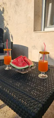 a table with a plate of watermelon and two glasses of juice at Nikolic Apartment 2 in Leskovac