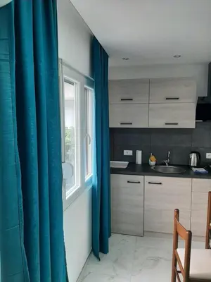 a kitchen with blue curtains and a sink and a window at Nikolic Apartment 2 in Leskovac