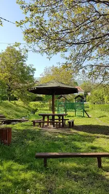 a picnic table with an umbrella in a park at Apartmani Smiljanic Sokobanja in Soko Banja