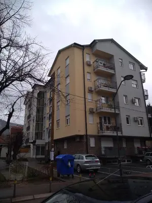 a tall building with a car parked in front of it at Apartman Dana in Soko Banja