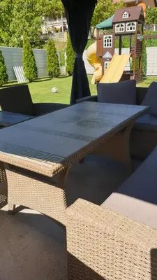 a wicker table and chairs with a playground in the background at Comfort Inn Apartmani in Vrnjačka Banja