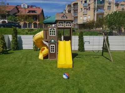 a playground with a house and a slide at Comfort Inn Apartmani in Vrnjačka Banja