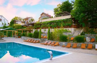 a swimming pool with chairs and a building at Apartman NEDA - 5 minuta od centra in Vrnjačka Banja