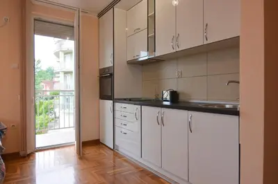 a kitchen with white cabinets and a large window at Apartman NEDA - 5 minuta od centra in Vrnjačka Banja