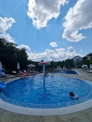 a person swimming in a pool with an umbrella at Apartman NEDA - 5 minuta od centra in Vrnjačka Banja