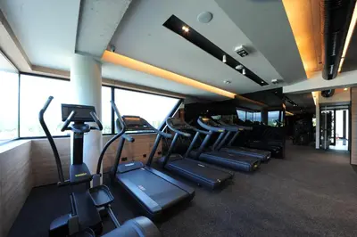 a gym with a row of treadmills and ellipticals at Hotel Royal Putnik in Vranje
