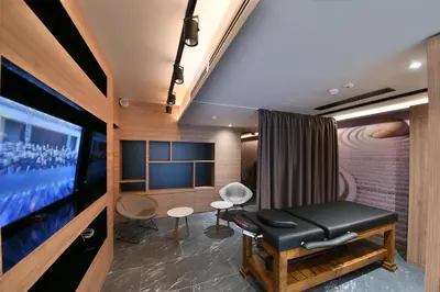 a room with a large screen tv and a table and chairs at Hotel Royal Putnik in Vranje