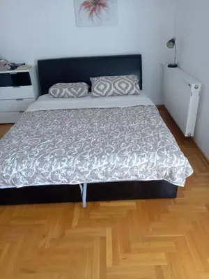 a large bed in a room with a wooden floor at Studio Apartman NENA in Vrnjačka Banja