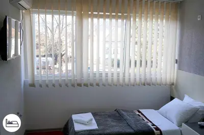 a bedroom with a bed and a large window at Rooms S&S Milicevic u strogom centru Aleksandrovca in Aleksandrovac