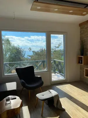 a living room with a chair and two large windows at Silver Hill apartment in Kopaonik