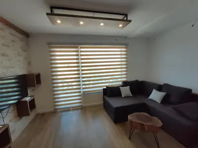 a living room with a black couch and a large window at Silver Hill apartment in Kopaonik
