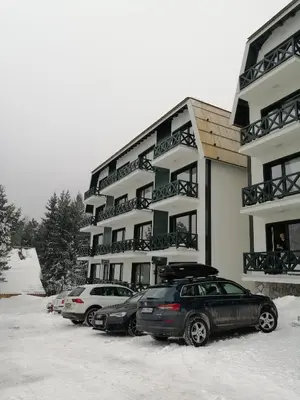 two cars parked in front of a building in the snow at Silver Hill apartment in Kopaonik