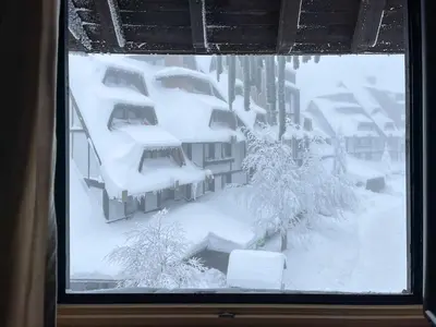 a window covered in snow with trees and buildings at Kopaonik Centar Konaci in Kopaonik