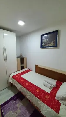 a bedroom with a bed with a red and white blanket at Apartmani Odmor i Mir in Vranje
