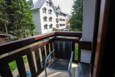 a chair sitting on a balcony with a building at Villa Zvončica, Apartman ViN in Kopaonik