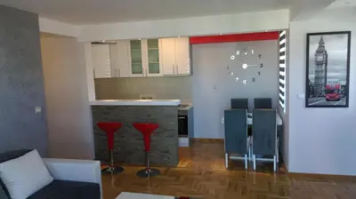 a living room with a kitchen and a bar with chairs at KIKI LUX Apartment in Vrnjačka Banja