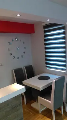 a dining room with a table and chairs and a clock at KIKI LUX Apartment in Vrnjačka Banja