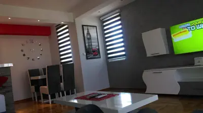 a dining room with a white table and a tv at KIKI LUX Apartment in Vrnjačka Banja