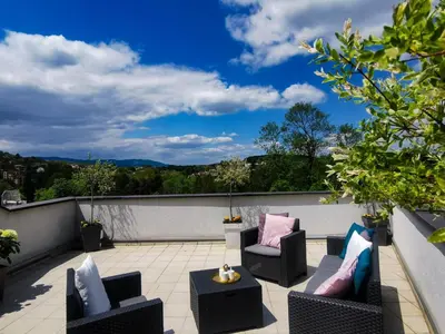 a patio with chairs and tables on a roof at Apartman Japanski vrt, Centar in Vrnjačka Banja
