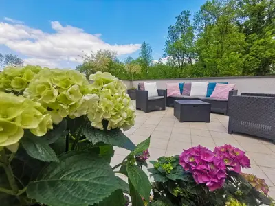 a patio with couches and flowers in a yard at Apartman Japanski vrt, Centar in Vrnjačka Banja