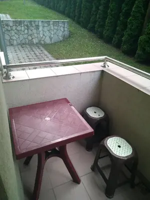 a table and two stools on a balcony with a window at Apartman Jacka in Vrnjačka Banja