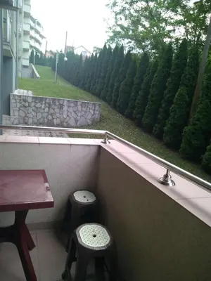 a balcony with two stools and a table and a window at Apartman Jacka in Vrnjačka Banja