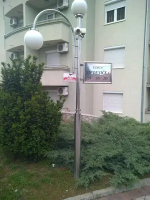 a street sign on a street light with a building at Apartman Jacka in Vrnjačka Banja