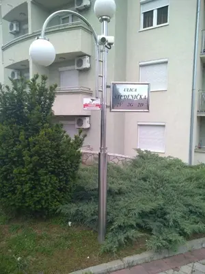 a street sign on a street light with a building at Apartman Jacka in Vrnjačka Banja