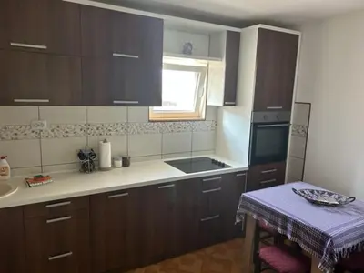 a kitchen with brown cabinets and a sink and a table at Seosko domacinstvo Vujic Sokobanja Resnik in Resnik