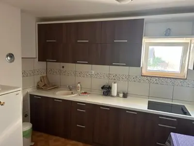 a kitchen with brown cabinets and a sink and a window at Seosko domacinstvo Vujic Sokobanja Resnik in Resnik