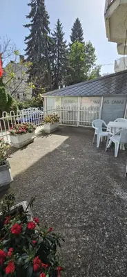 a patio with white chairs and flowers and a fence at Apartman Casa Lux in Vrnjačka Banja