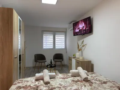 a bedroom with a bed with a tv on the wall at Relax Apartmani Niš in Niš