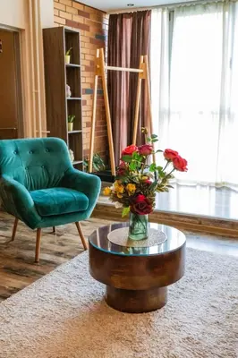 a living room with a green chair and a table with flowers at City apartment and gym in Niš