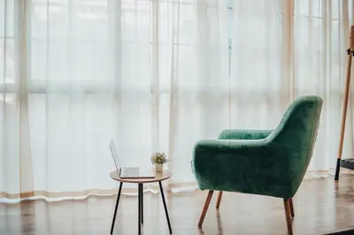 a green chair and a table with a laptop on it at City apartment and gym in Niš